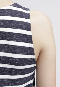 Szaro-biały, prążkowany top na ramiączkach o miękkiej teksturze, prezentujący bezrękawowy krój i okrągły dekolt.