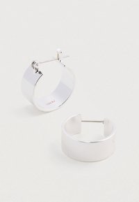 Srebrne kolczyki w kształcie kół o gładkiej, refleksyjnej powierzchni, charakteryzujące się minimalistycznym designem i bezpiecznym zapięciem na sztyft.