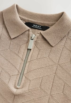 Beige Strick-Polohemd mit einem Reißverschluss vorne, das ein strukturiertes geometrisches Muster und einen weichen Kragen aufweist. Markenlabel sichtbar im Kragen.