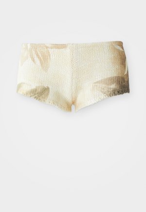 Strikkede shorts i lys beige med blomstermønster. Har en strukturert overflate og bølget kant. Mykt og lett stoff.