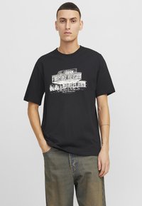 Camiseta de algodón negra con estampado gráfico blanco con el texto "Originals". Corte holgado, mangas cortas y escote redondo.