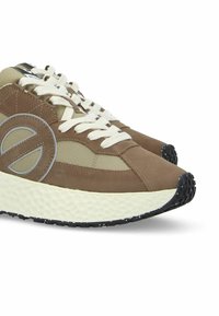 Bruine en beige sneakers met een textiele bovenkant van leer, rond logo aan de zijkant, witte veters en een zwarte rubberen zool.