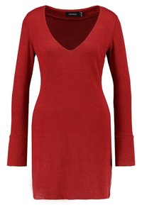 Röd stickad klänning med långa ärmar, V-ringning och utsvängda ärmslut. Mjuk textur och knälång design med sidopluppar för ökad rörelsefrihet.