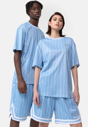 Conjunto de ropa deportiva azul claro que incluye camisetas de malla oversized y pantalones cortos con rayas blancas y marca, diseñado con un ajuste relajado.