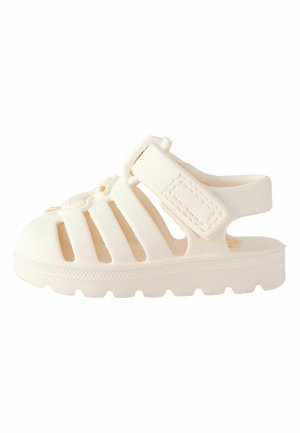 White rubber sandal with cut-out design, adjustable strap, and textured sole. Features a rounded toe and a solid, durable construction.