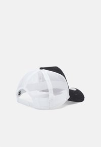 Casquette noire à l'avant avec un dos en maille blanche. Présente une forme arrondie et une fermeture à pression. Coutures visibles et détail du logo à l'avant.