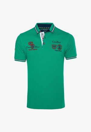 Grøn polo t-shirt med korte ærmer, med en marineblå stribet krave og manchetter, med røde og sorte rugby league logoer på brystet og ærmet.