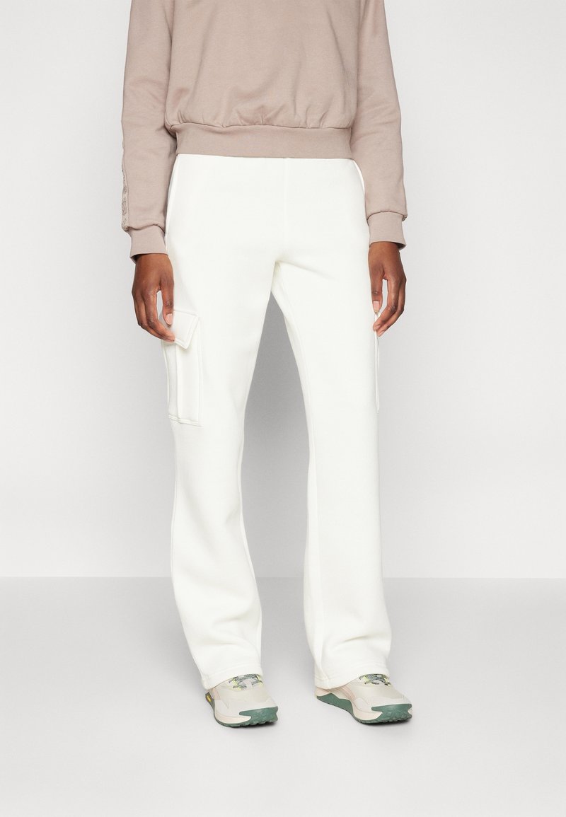 Hvide bredbenede cargo-bukser med to sidelommer, lavet af blødt stof. Bæres med en beige sweatshirt og sneakers i lyse farver.