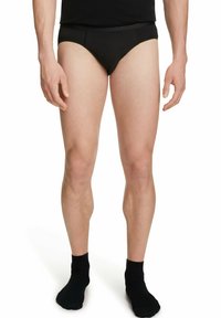 Zwarte herenonderbroeken van een gladde stof, met een elastische tailleband en een aansluitend design. Model staat met de benen bij elkaar, met zwarte sokken aan.