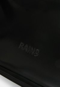 Černá voděodolná taška s matným povrchem, vyznačující se vyraženým logem "RAINS". Obdélníkový tvar, hladká textura a minimalistický design.