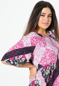 Vícebarevné šaty s květinovými vzory v růžové, černé a zelené barvě. Mají krátké rukávy a nabranou sukni s kulatým výstřihem.