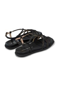 Czarne płaskie sandały z krzyżującymi się paskami, górny pasek z małą okrągłą klamrą. Teksturowana czarna wkładka z widoczną nazwą marki.