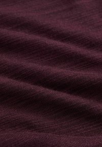 Stofă texturată color burgund cu un aspect moale, cu nervuri, având variații subtile în nuanță și adâncime pe întreaga suprafață.