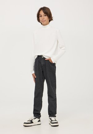 Maglietta bianca a maniche lunghe con colletto a dolcevita, jeans grigi scuri a gamba affusolata, scarpe da ginnastica nere e bianche, look informale, design semplice, texture del tessuto visibili.