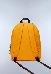 Mochila amarilla con correas y asa negras, que tiene una forma redondeada, textura de tela y un bolsillo con cremallera en el lateral. Superficie lisa con detalles mínimos.