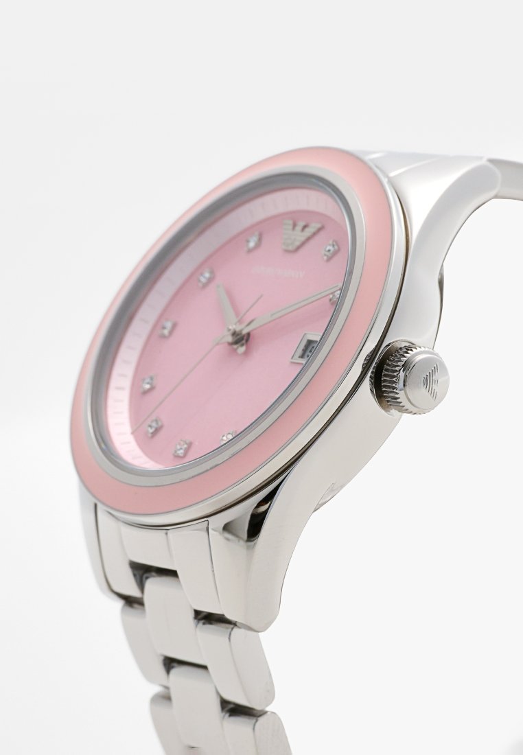 Reloj de pulsera plateado con esfera rosa, detalles de cristal y un bisel liso. Cuenta con una pulsera de acero inoxidable y una corona en el lateral.