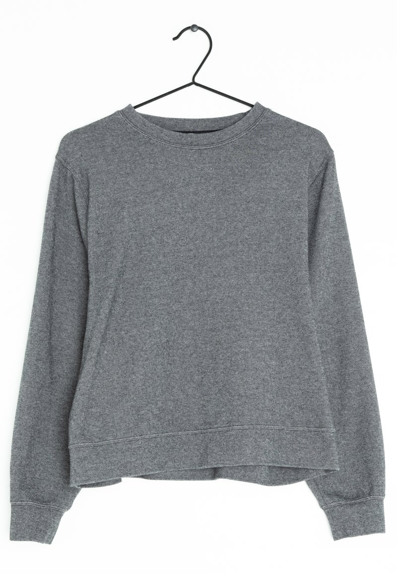 Sweat-shirt gris à manches longues suspendu à un cintre en métal noir, avec un col rond et des poignets côtelés, présenté sur un fond blanc.