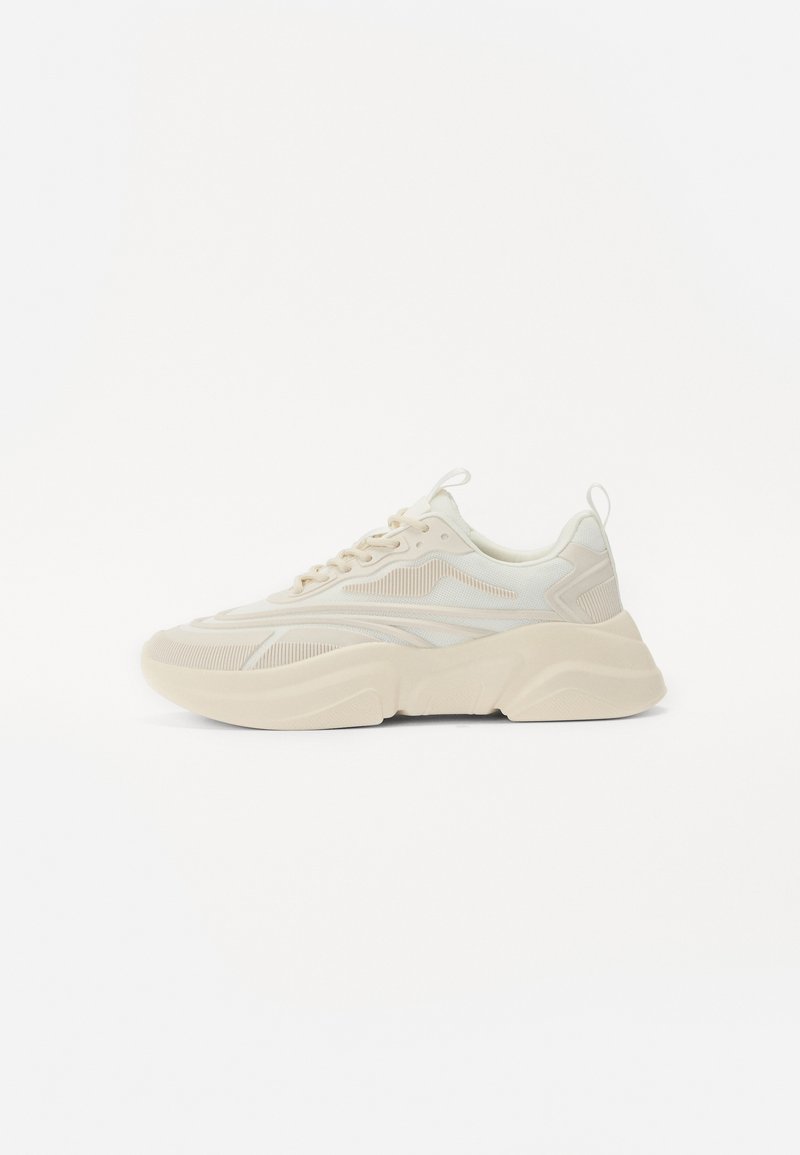 Chunky sneakers i creme med en tekstureret overdel, snørebåndslukning, forstærket hæl og en karakteristisk lagdelt sål. Diskrete striber og akcenter hele vejen igennem.