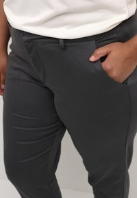 Grå, skräddarsydda byxor med en jämn konsistens, som har en framficka och en slim fit-design. Tyget verkar vara lätt och skräddarsytt mot rynkor.