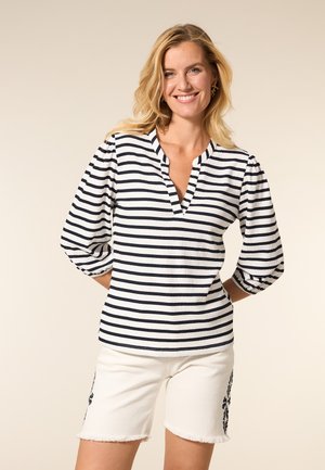 Gestreepte blouse met lange mouwen en een aangeklede kraag in wit en marineblauw. Kenmerkt zich door een gestructureerde stof en een ontspannen pasvorm. Gecombineerd met witte shorts.
