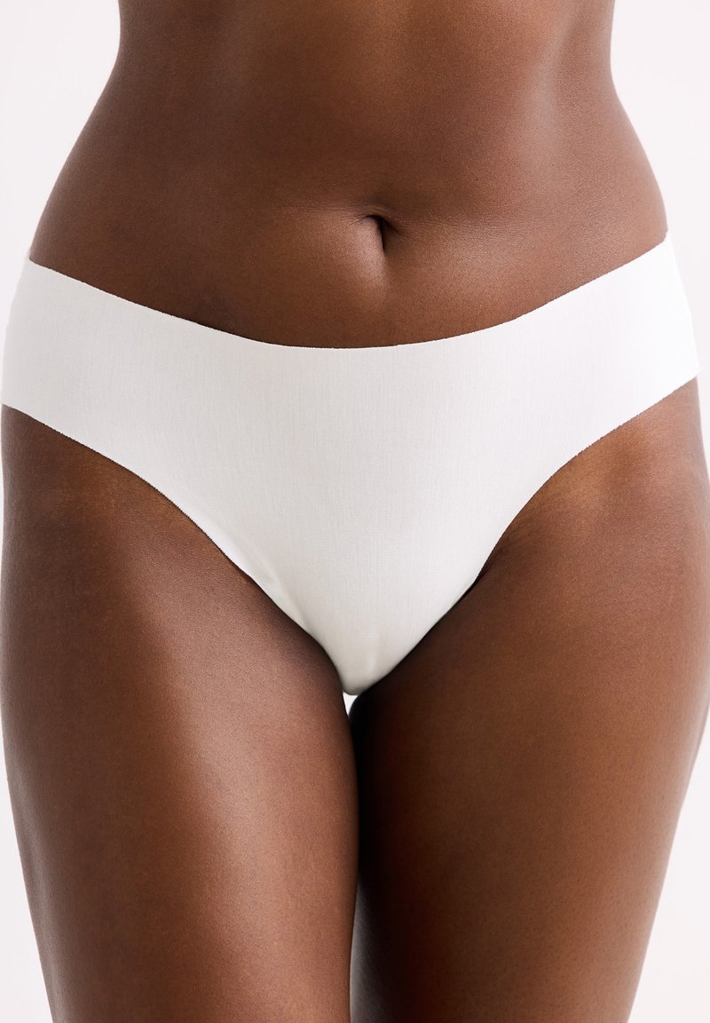 Witte naadloze dames bikini slipjes van zacht materiaal, met een hoge taille en een gladde textuur, die een minimalistisch ontwerp bieden.