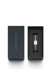 Gold mesh strap watch in a dark blue box. Rectangular white face with gold accents, displayed on soft black interior padding.