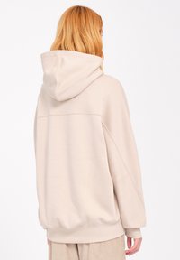 Beige hoodie with a drawstring hood, drop shoulders, and ribbed cuffs. Soft fabric with a smooth texture and a clean, minimalist design.