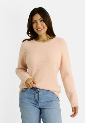Suéter rosa claro, suave, con mangas largas, cuello redondo y un corte ligeramente holgado, combinado con jeans azules de tiro medio.