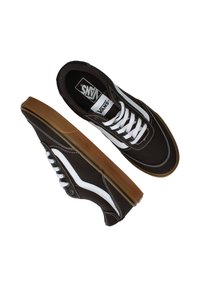 Bruine canvas sneakers met witte accenten en veters. Voorzien van een gumrubberen zool en het kenmerkende Vans-logo op de tong. Klassiek low-top ontwerp.