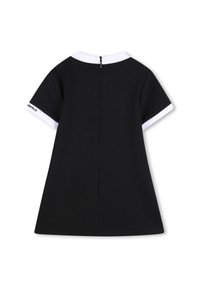 Μαύρο φόρεμα με λευκό γιακά, κοντά μανίκια και φερμουάρ στην πλάτη. Διαθέτει λεπτομέρεια λογότυπου στο μανίκι και φουσκωτή σιλουέτα.