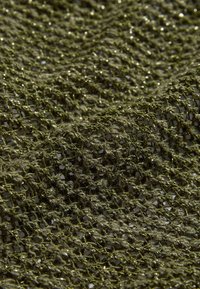 Tissu en maille texturé de couleur vert olive avec un motif de tricot lâche et des détails subtils brillants, créant profondeur et dimension.