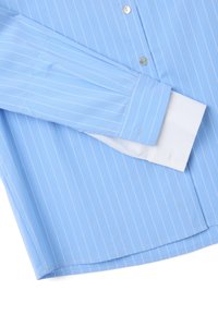 Camisa de dress de rayas finas azul claro con puños y botones blancos que contrastan, doblada ordenadamente sobre una superficie blanca.