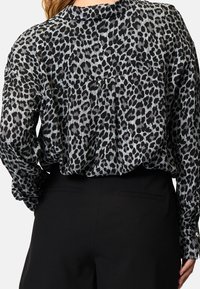 Schwarze und graue Bluse mit Leopardenmuster, lockerer Passform, runder Ausschnitt und geknöpften Manschetten. Texturiertes Gewebe mit weichem, fließendem Fall.