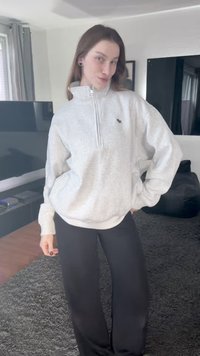 Pilkas užsegamas džemperis su aukštu apykakliu ir mažu logotipu. Derinamas su juodomis plačiomis kelnėmis. Minkšta, lengva medžiaga.