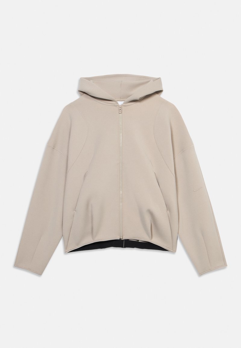 Φωτεινό μπεζ φούτερ με φερμουάρ, μαλακό ύφασμα, άνετη γραμμή, μεγάλο κουκούλι, χαμηλωμένοι ώμοι, με διακριτική μαύρη λεπτομέρεια στο κάτω μέρος.