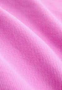 Ružová rebrovaná látka s vertikálnou textúrou. Mäkka, plyšová površina s jemným leskom, jemne sa skladajúca sama na seba.