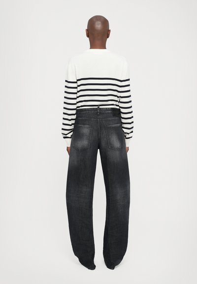 Black denim wide-leg pants with a faded finish, paired with a white and black striped long-sleeve shirt featuring ribbed cuffs.