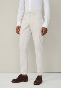 Lichtbeige chinos met een klassiek ontwerp, rechte pasvorm, ritssluiting en voorkwakken. Gecombineerd met donkerbruine suède nette schoenen.