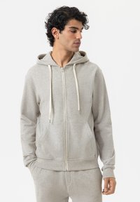 Felpa zip grigia chiara in morbido cotone misto. Caratterizzata da un cappuccio, tasche frontali, cordini crema e polsini a costine. Texture liscia, vestibilità casual.