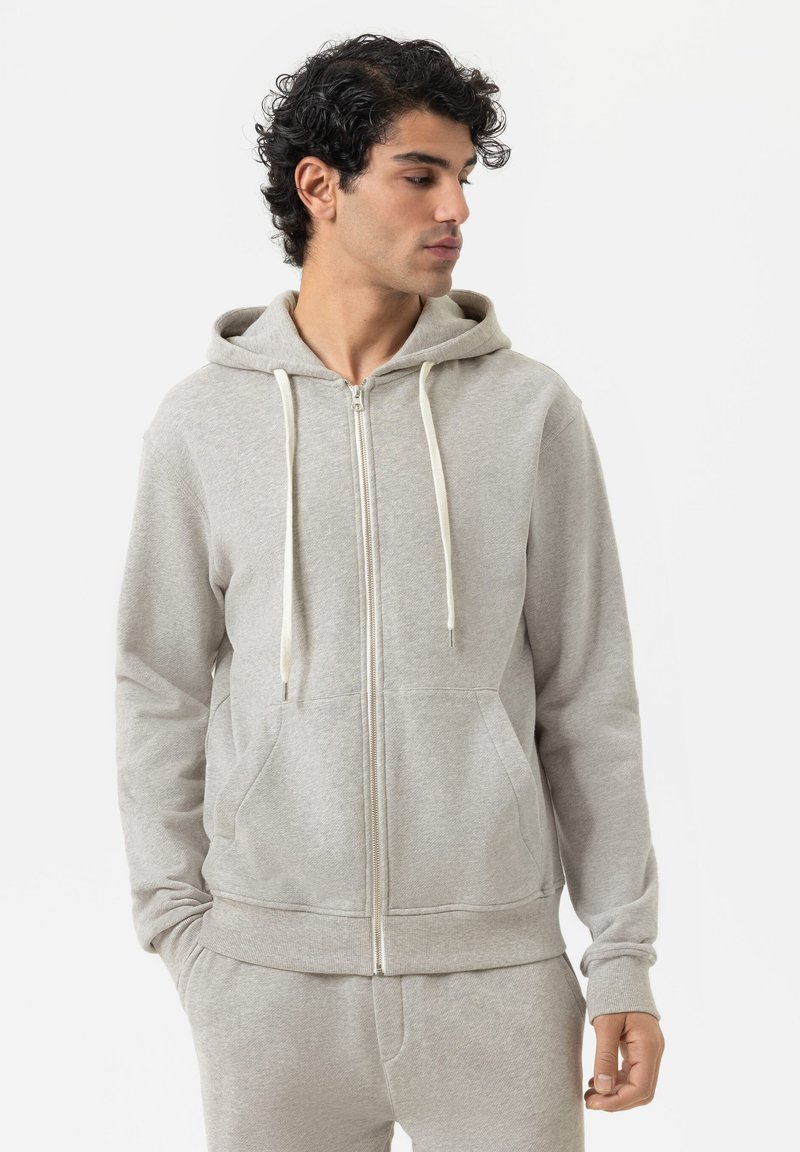 Felpa zip grigia chiara in morbido cotone misto. Caratterizzata da un cappuccio, tasche frontali, cordini crema e polsini a costine. Texture liscia, vestibilità casual.
