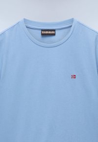 Light blue cotton t-shirt with a round neck. Features a small embroidered Norway flag near the chest. Soft texture, casual design.
