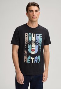 Zwarte katoen T-shirt met een retro grafische print van het gezicht van een vrouw, met de tekst "ROUGE" en "RETRO" in blauw, beige en witte kleuren.