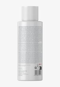 Bouteille en plastique blanche avec un capuchon strié, en forme cylindrique. L'étiquette présente plusieurs langues avec des symboles de sécurité et une liste d'ingrédients.