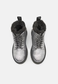 Zilveren leren enkellaarsjes met een gebroken textuur, nepbont voering en zwarte veters. Voorzien van een trekband en stevige rubberen zool.