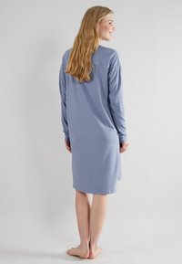 Camicione da notte a maniche lunghe in morbido tessuto blu, con un fit rilassato, scollatura a girocollo e orlo fino al ginocchio con leggere spacco laterali.