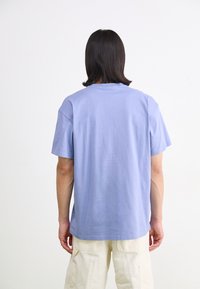 Light purple cotton t-shirt with short sleeves, round neckline, and a relaxed fit. Smooth texture with minimal stitching details.
