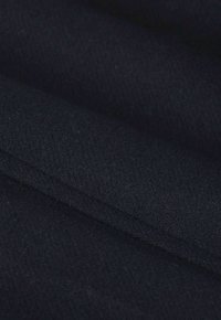 Tissu bleu marine foncé avec une surface lisse et légèrement texturée, présentant des couches pliées qui créent de la profondeur et des ombres subtiles.