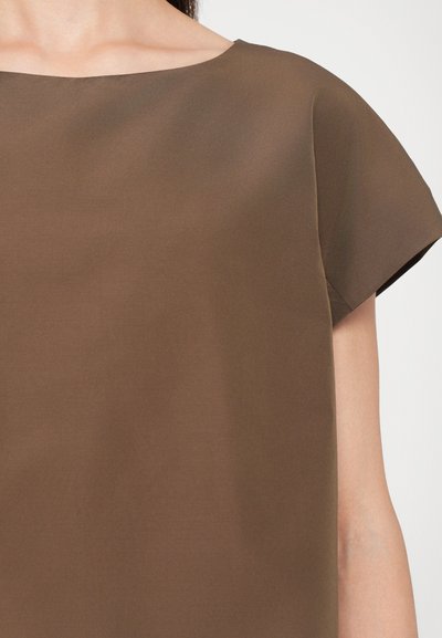 Haut marron à manches courtes avec une coupe décontractée, fabriqué en tissu lisse. Il présente un col rond et un design minimaliste.