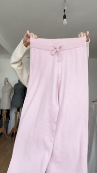Pantalon de survêtement rose clair avec une taille élastiquée côtelée et un cordon de serrage ajustable, présentant une texture douce et une coupe décontractée à jambes larges.