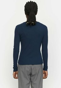 Marineblauw longsleeve shirt met geribbelde textuur, aansluitend ontwerp en ronde hals, gecombineerd met lichtgrijze broek.